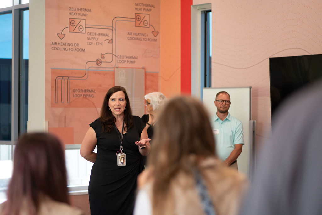 Kerri addressing a crowd at the school in front of a diagram of geothermal heat pumps
