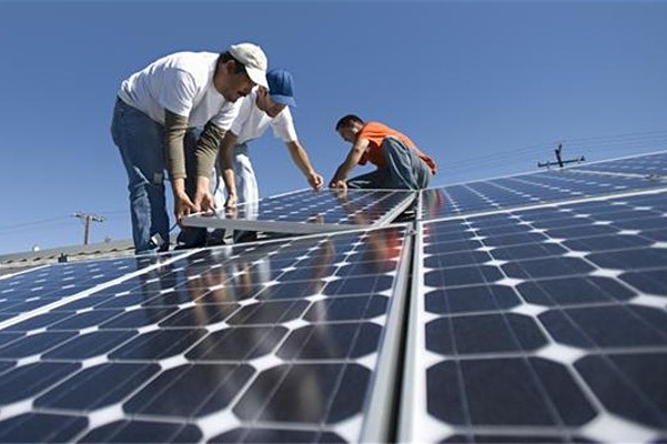 three people installing solar panels