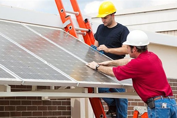 two people inspecting solar panels on building