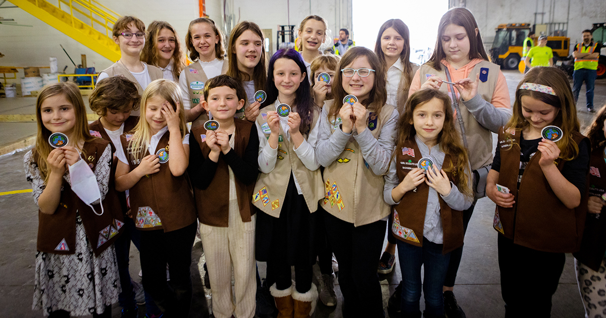 The Girl Scout troops holding up their newly acquired patches