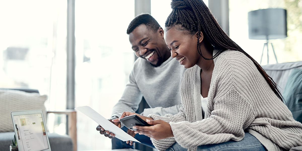 Smiling couple using a calculator and laptop