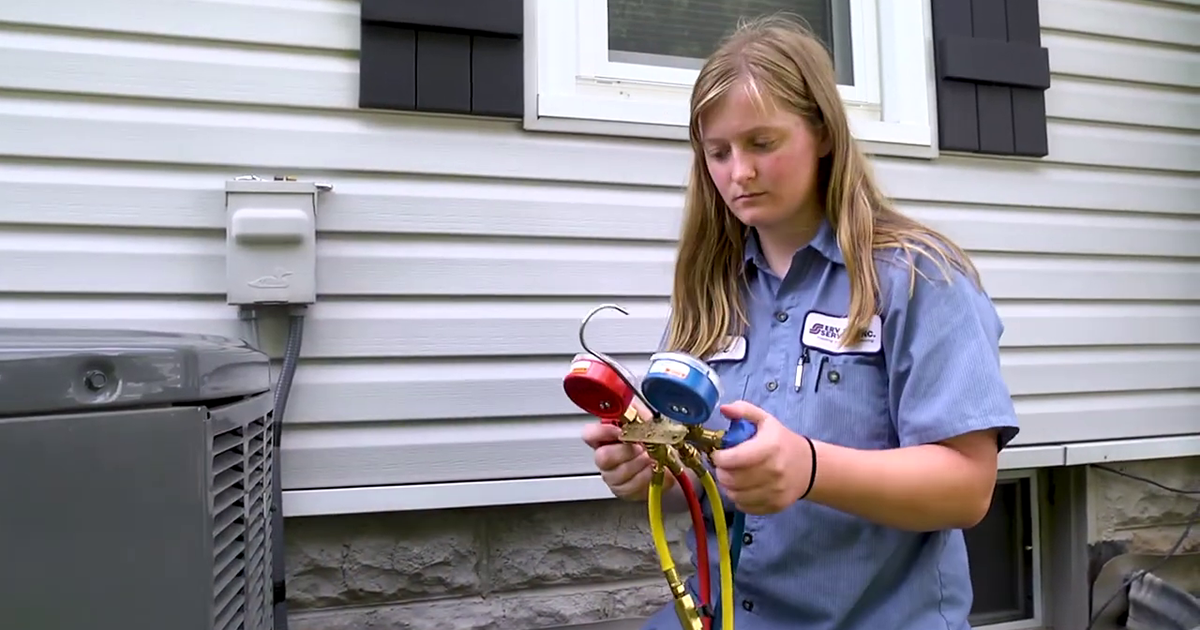 A young technician learning to service an air conditioning unit