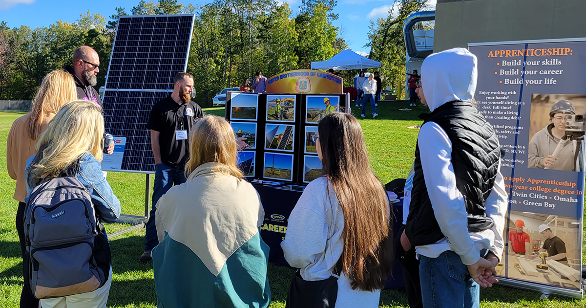 Students observe a demonstration of solar panels at an outdoor career fair