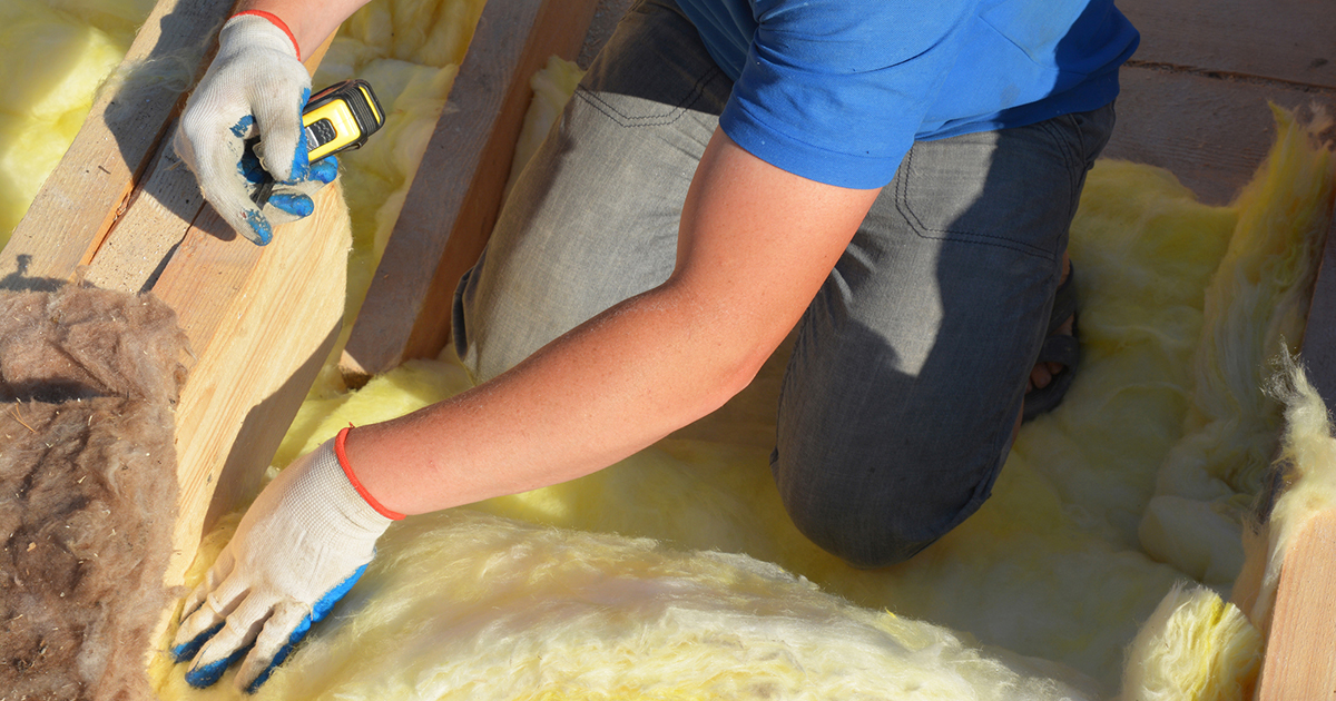 A worker adding insulation to a roof