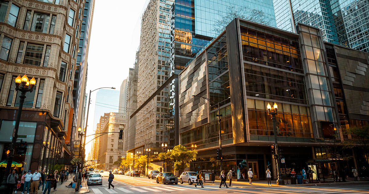 A photograph of Chicago showing multiple commercial buildings and people walking in a crosswalk