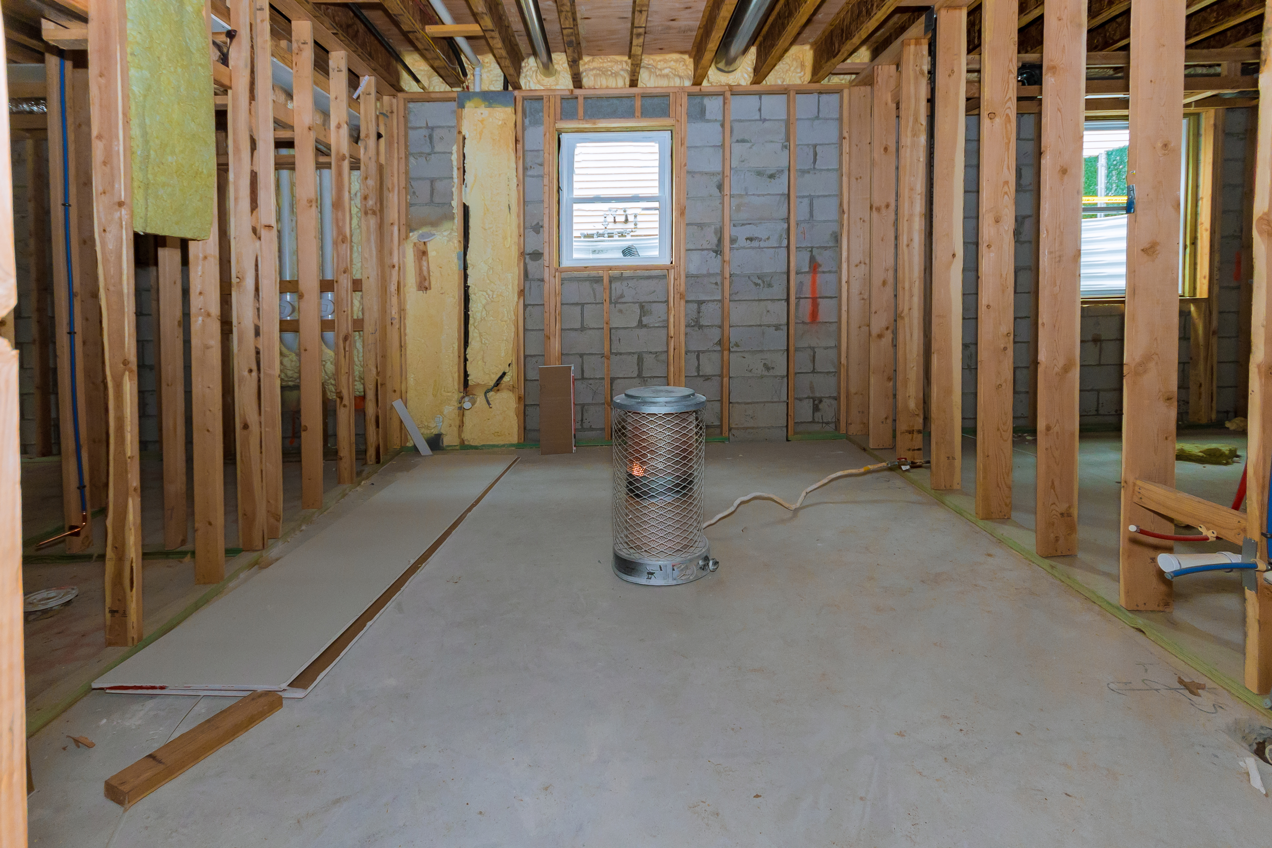 Home under construction with a space heater in the middle of the room.