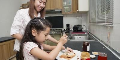A mother and child making a PB&J sandwich at home