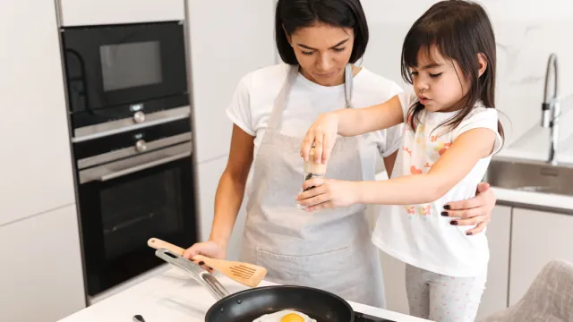 A photo of a mother and child cooking eggs in their kitchen