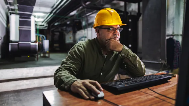 An engineer looking at a computer in a building control room
